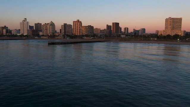 Drone view over Indian Ocean to Durban beachfront skyline at sunrise.