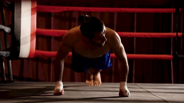 Strong Caucasian sportsman boxer doing push-up exercises on boxing ring preparing body for punching. Look strength of body and summon strength to prepare for exercise at the corner of the boxing ring.