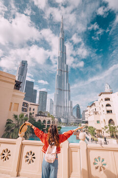 18 January 2023, Dubai, UAE:  Happy girl arms are outstretched, as she embracing the incredible view before her with unreal Burj Khalifa tower in Dubai, UAE