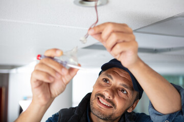 a male electrician fixing light on the ceiling