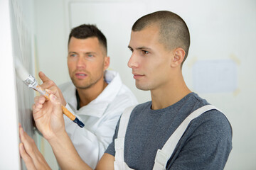 Fototapeta premium apprentices learning how to paint with a thick brush