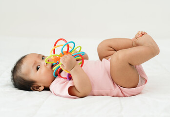 infant baby biting colorful rubber bites toy on bed
