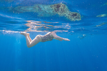 Fototapeta na wymiar The girl swims underwater in the sea.