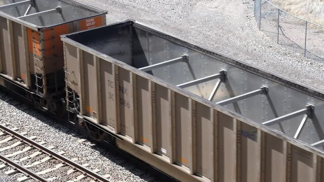 Empty hopper cars of freight transport train passing by. High angle zoom
