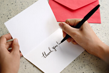 Female hands writing a thank you note with envelope