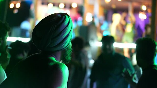 Indian men dance at night club. Male sikh wear turban hat. Crazy arab have fun nightclub party. India pop rave fest. Joyful guy hang out. Native hindu dancer rest. Local head dress. Neon Generative AI