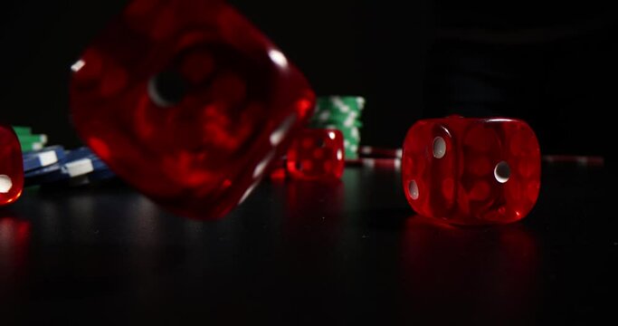 Red Transparent Dices Fall By Expensive Playing Casino Chips. Casino Chips And Dices On Black Surface Under Studio Light. Equipment For Playing Professional Gambling Games