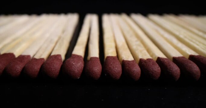 Long flat row of thin aspen matches with red sulfur heads arranged in line. Wooden matchsticks for getting fire while cooking on dark background background