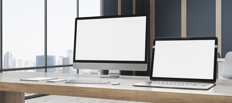 Contemporary designer office workspace with empty white mock up computer screens, supplies and blurry interior with windows and city view background. 3D Rendering.