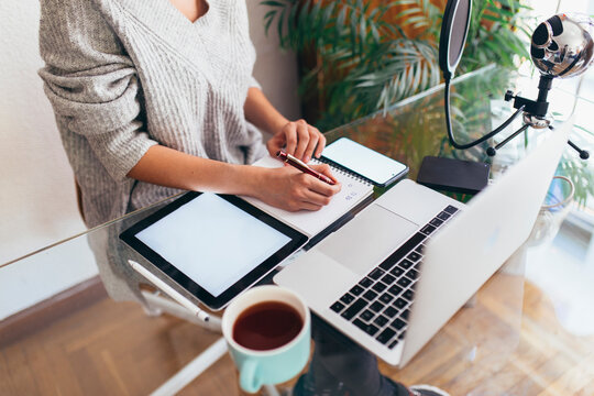 Podcaster writing in diary at desk in home office - Powered by Adobe