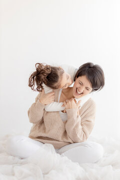 Happy mother and daughter having fun in front of white wall