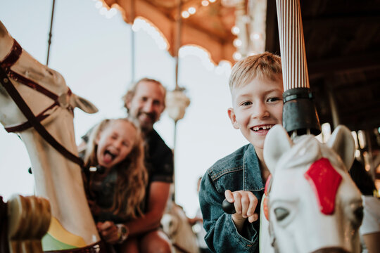 Smiling boy enjoying carousel ride with family at amusement park