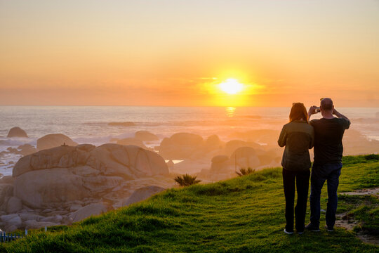 South Africa, Western Cape Province, Cape Town, Tourists photographing Atlantic Ocean at sunset