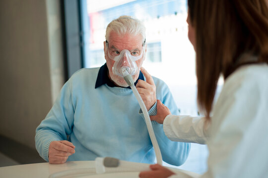 Doctor assisting patient wearing nebulizer at clinic