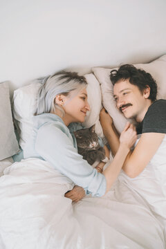 Smiling woman embracing man lying on bed at home