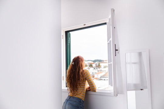 Redhead Woman Looking Out Of Window From Hotel Room