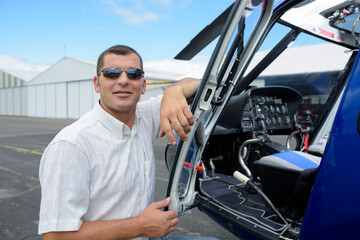 portrait of pilot standing in front of helicopter © auremar