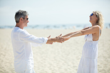 carefree older couple holding hands with outstretched arms