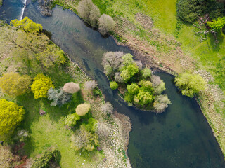 Drone view of a fresh water river seen entry from a large lake. A small natural river Island is seen. In the area of rare white deer which can be seen grazing below.