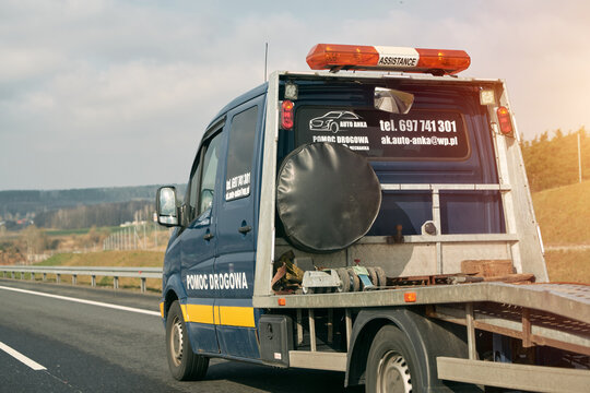15.04.2023 Europe, Germany. Tow truck with broken car on country road. Tow truck transporting car on the highway. Car service transportation concept.