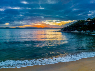 Aerial sunrise seascape with calm seas and a mix of high and low cloud