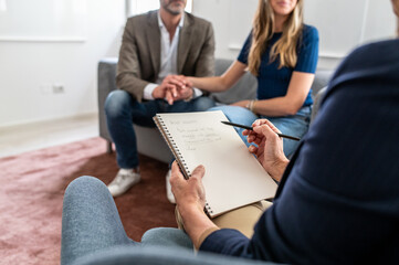 Psychological therapy of a young couple, point of view of the female therapist taking notes