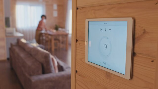 Medium close-up selective focus shot of smart home climate control system app on tablet screen