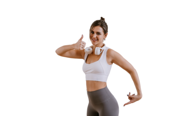 brunette hispanic girl in sportswear shows thumb up gesture, points on buttocks satisfied by body shape and physical form. Healthy lifestyle. Young woman in headphones against transparent background