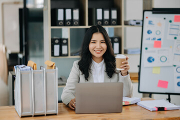 Young attractive Asian female office worker business suits smiling at camera in modern office .