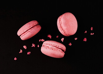 Pink macarons flying above a black table. Top shot, dark background. Creative food concept.