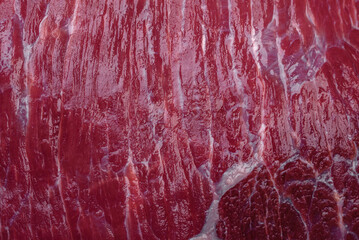 A piece of fresh raw beef with salt, spices and herbs on a wooden cutting board