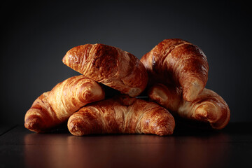 Freshly baked croissants on a black ceramic table.