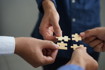The concept of teamwork and partnership Hands joining puzzle pieces in office Businessmen put together a jigsaw puzzle - volunteer charity team business uniy. - obrazy, fototapety, plakaty