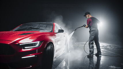 Portrait of an Adult Man Working in a Detailing Studio, Prepping a Factory Fresh Red Sportscar for...