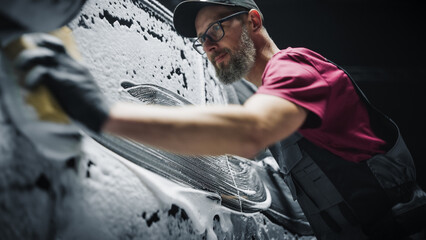 Portrait of an Adult Man Working in a Detailing Studio, Prepping a Factory Fresh Electric SUV for...