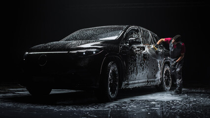 Portrait of an Adult Man Working in a Detailing Studio, Prepping a Factory Fresh Electric SUV for...