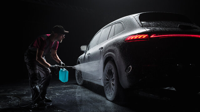 Professional Car Wash Specialist Spraying Smart Foam to Prepare a Modern Black Electric SUV with Contemporary Design for Sale at a Dealership Car Center. Commercial Studio Footage for Advertising