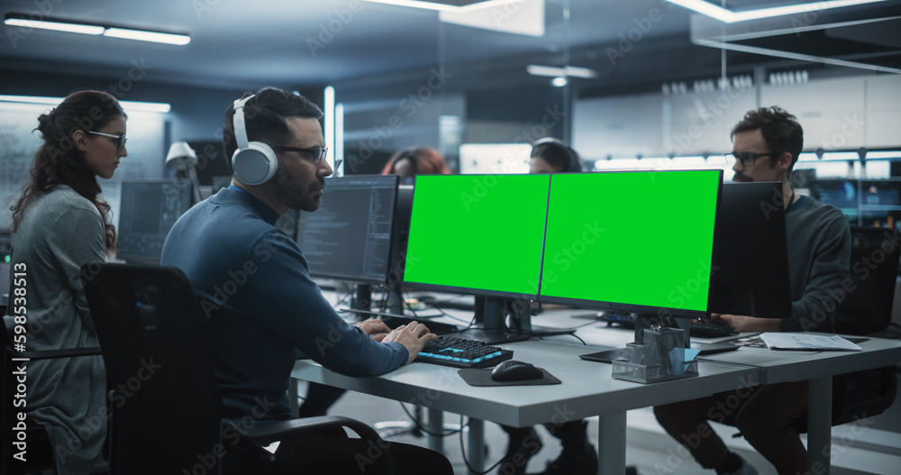 Poster Group of Diverse Multicultural Men and Women Working on Desktop Computers in a Research Center. Young Software Developer Working on a Computer with Two Green Screen Mock Up Displays