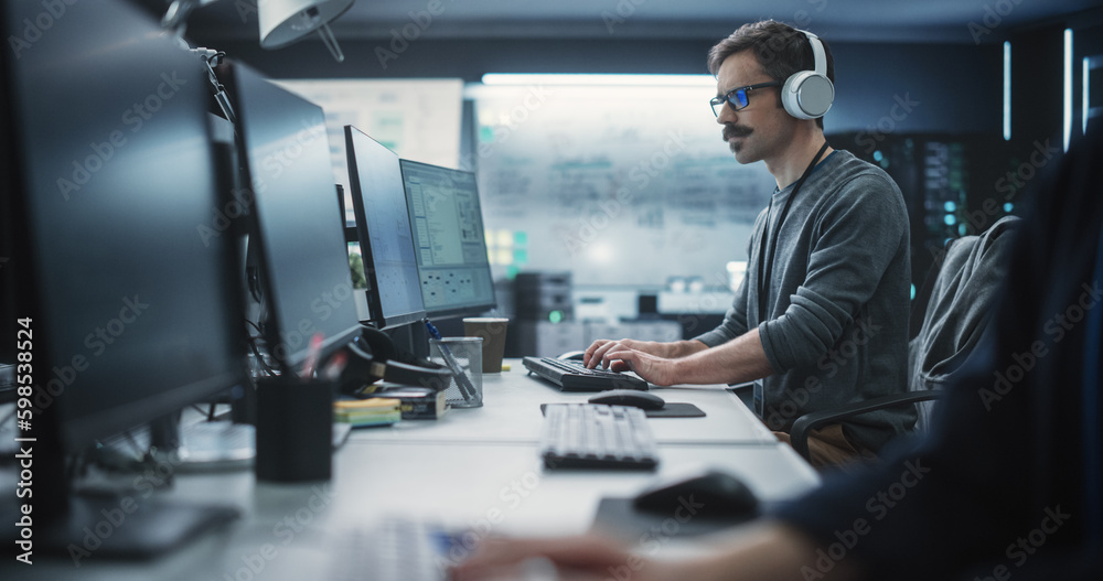 Poster System Administrator Working in a Research E-Business Facility on a Desktop Computer. Focused Software Developer in Casual Clothes Wearing Headphones and Updating Server System Database