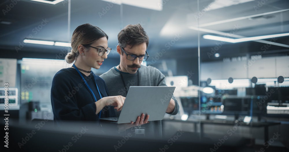 Poster Portrait of Two Creative Young Female and Male Engineers Using Laptop Computer to Analyze and Discuss How to Proceed with the Artificial Intelligence Software. Standing in High Tech Research Office