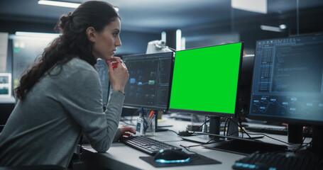 Female Software Developer Working on a Desktop Computer with Green Screen Mock Up Display....