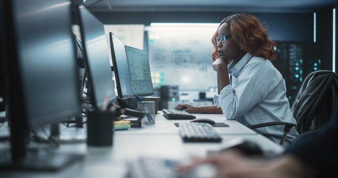 Focused Young African American Female Software Developer Working on Computer Together with Two Creative Male Colleagues. Data Protection Center with Servers, Storage Hardware and eBusiness Research