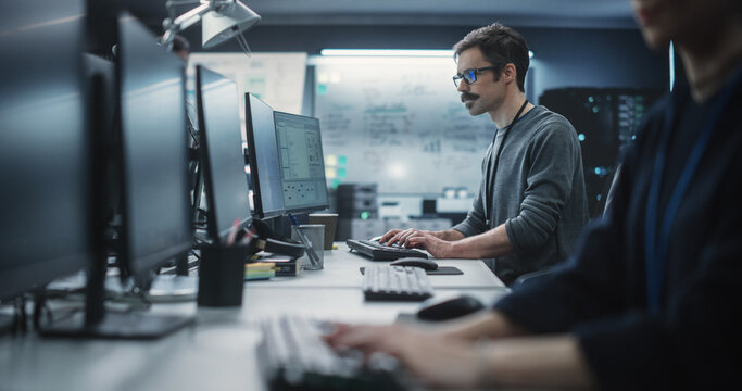 Portrait of a Thoughtful Engineer Working on Desktop Computer in a Technological Office Environment. Research and Development Department Writing Software Code for an Innovative Internet Project