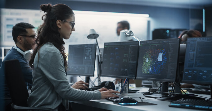Young Female Artificial Intelligence Engineer Working on Computer in a Technological Office. Young Specialist Writing Software Code for an Innovative Big Data Blockchain Project. Photo from the Back - Powered by Adobe