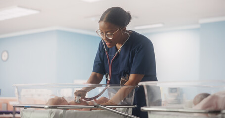 Happy Professional Nurse Providing Around-the-Clock Care to a Recovered Preterm Baby in Neonatal Intensive Care Unit. African Female Doctor Checking Up on a Child, Using Stethoscope in Nursery Clinic - obrazy, fototapety, plakaty
