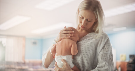 Young Happy Mother Holding Her Newborn Child, Bonding with Little Infant in Modern Maternity Hospital. Blessed Caucasian Woman Soothing Her Baby. Medical Health Care, Maternity and Parenthood Concept