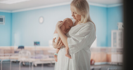 Young Happy Mother Holding Her Newborn Child, Bonding with Little Infant in Modern Maternity Hospital. Blessed Caucasian Woman Soothing Her Baby. Medical Health Care, Maternity and Parenthood Concept