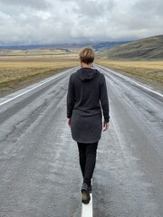Young woman walking into the distance along the road