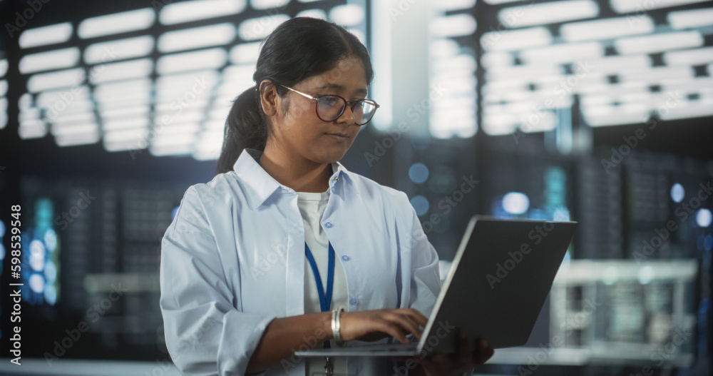 Poster Portrait of a Technological Software Engineering Department Manager Standing and Using a Laptop Computer. Indian Female Focused on Thinking while Working in the Office