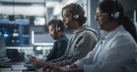 Fototapeta premium Positive Technical Support Managers Talking on Calls, Providing Help Desk Solutions to Customers Experiencing Troubleshooting Issues with a Product. Indian Specialists Successfully Solving Problems
